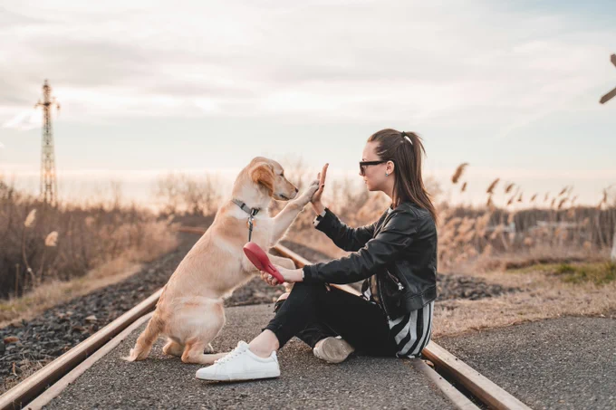 Una mujer chocando los cinco con su perro 