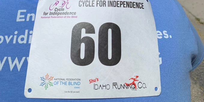 Close up image of the Cycle for Independence race bib worn by an NWABA cycling guide #60.