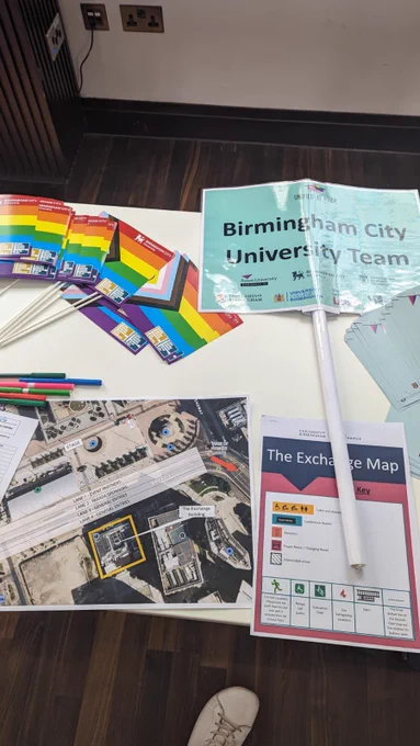 Photo of a banner saying “Birmingham City University team” & Progress Prode flags on a white table