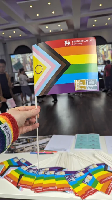 Photo of a hand holding a BCU Progress Pride flag
