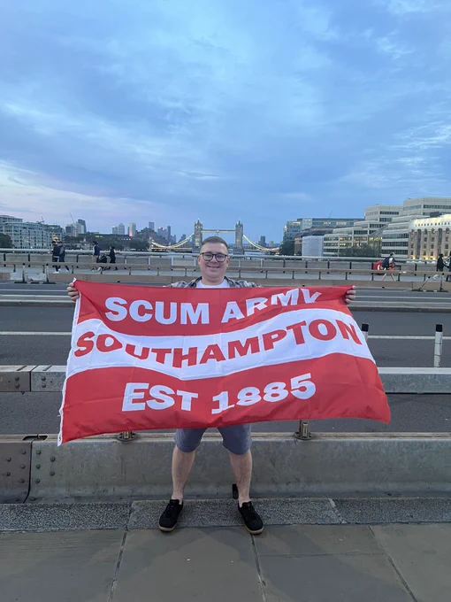 Josh holding a Saints football fan flag on Tower Bridge