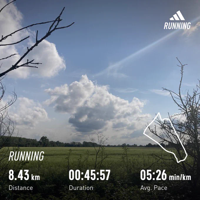 View across a field in the sun with a few clouds in the sky; running stats superimposed (8.43km, 45:57)
