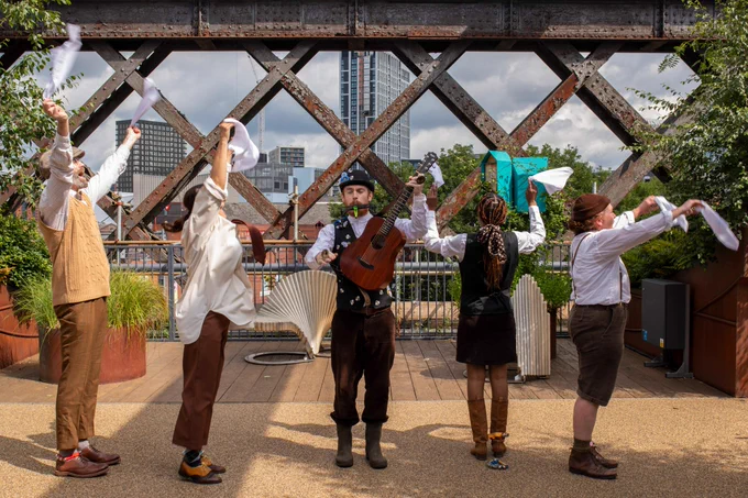 Five performers dressed in costume performing on Castlefield Viaduct