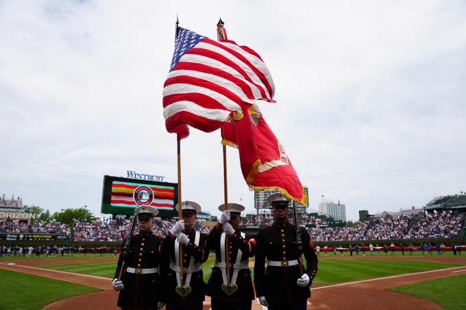 The Color Guard presents the American flag during the national anthem at Wrigley Field. A giant flag is unfurled in the outfield.