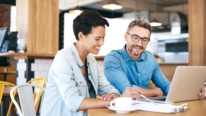 A woman and a man discuss the finances of a small business 