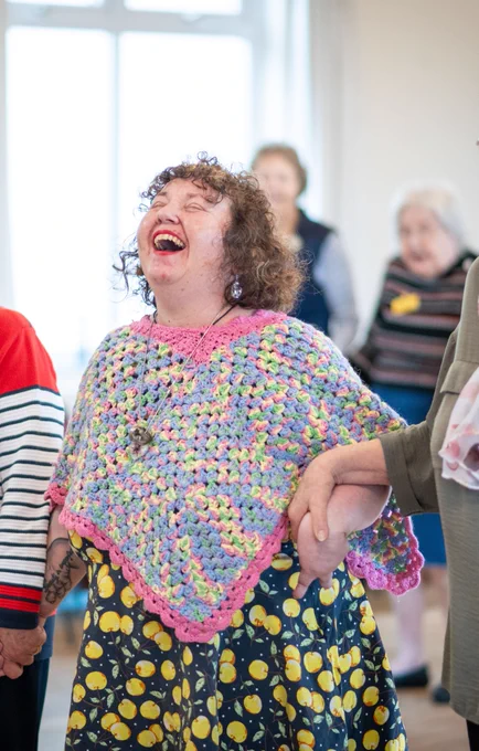 A woman throws her head back and laughs as she dances in a row of people