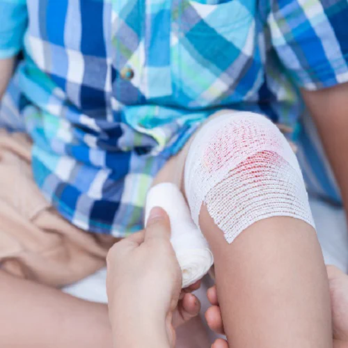 A child's grazed knee being bandaged.
