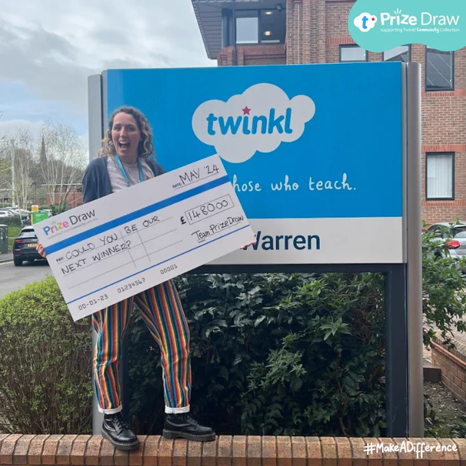 The image shows a smiling woman holding an oversized check for £148,000 from Twinkl. She is standing in front of a large outdoor advertising display for Twinkl, featuring their logo and the slogan "Those who teach."