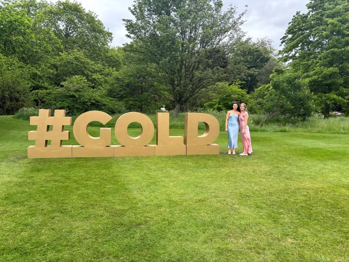 Photo of two young people next to a #Gold sign.