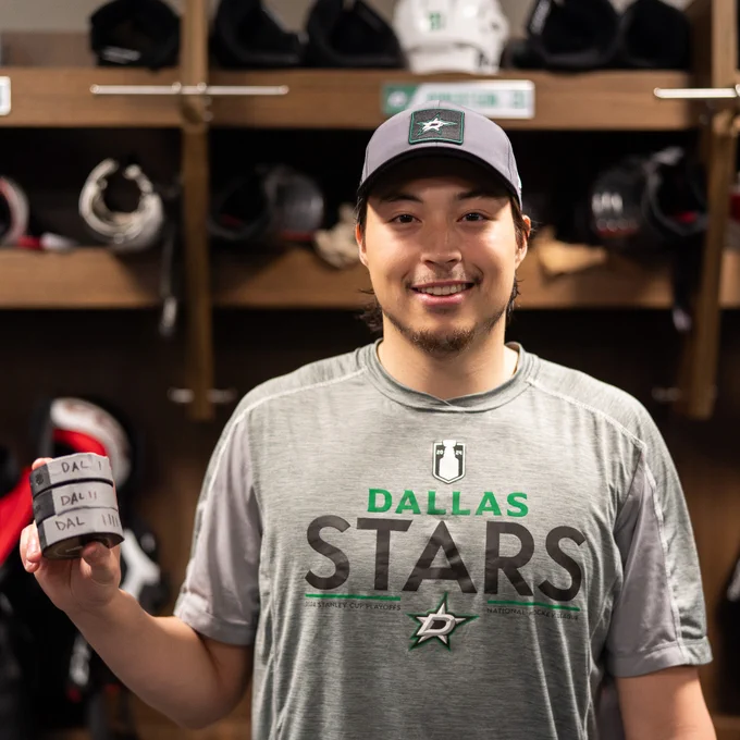 Jason Robertson holds his three pucks from his hat trick in front of his stall in the locker room