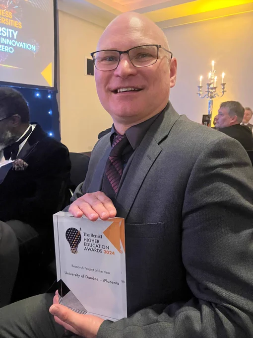 Dr Colin Murdoch holding the Herald Higher Education Award given to his project iPlacenta