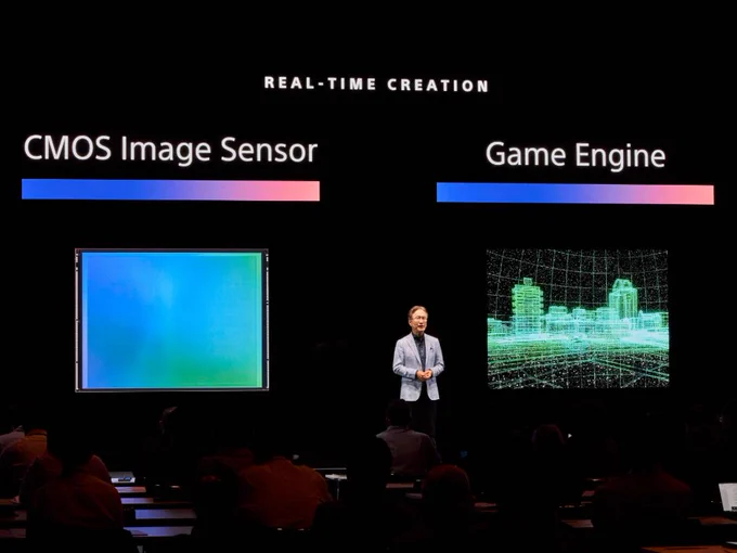 Photo of Sony Chairman and CEO Kenichiro Yoshida on stage giving a presentation to participants. Behind him, the phrases "CMOS Image Sensor" and "Game Engine" are projected in large letters.