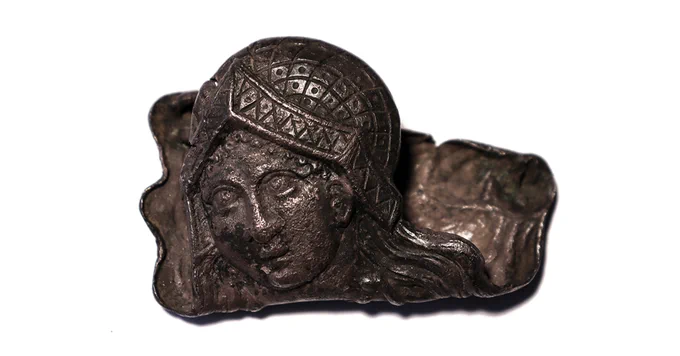 A silver badge featuring a woman's face.