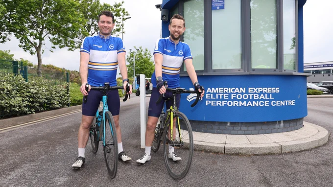 Stuart and Jonny stood with their bikes outside the entrance of our training ground.