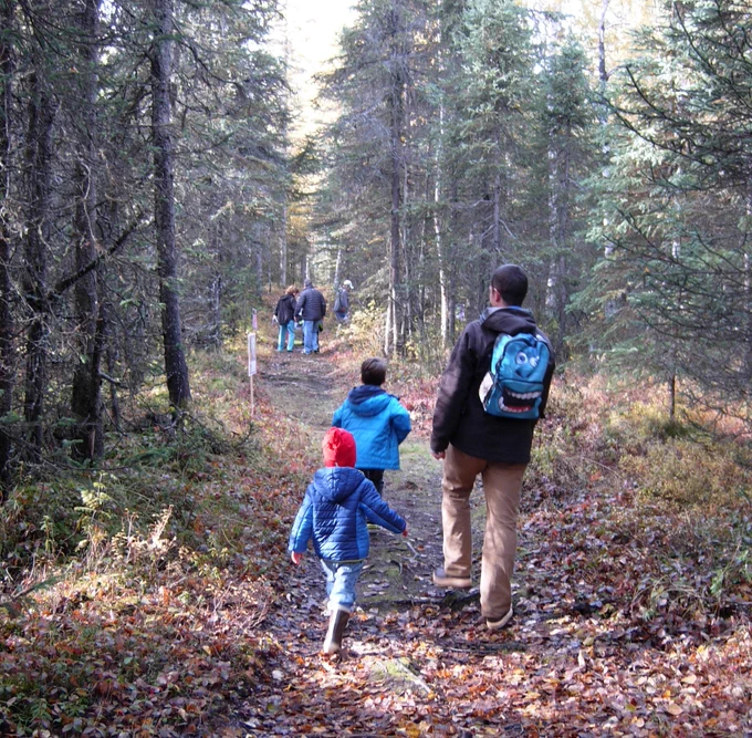  Kids and adults take a hike! down a mushing trail on Campbell Tract in 2023. 
Photo by BLM. 

Alt Text: Children and adults walking through a spruce-birch forest on a narrow trail. 