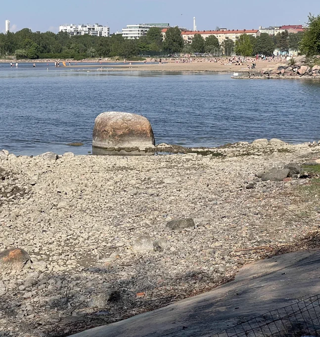 Hietaniemen uimaranta Ourit-saaresta nähtynä helteisenä toukokuun päivänä. Etualalla alhaisen vedenpinnan paljastamaa soraikkoa.