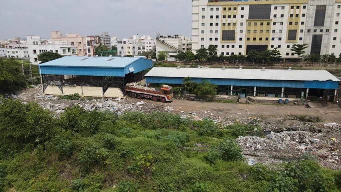 A trash collection facility with a truck full loaded with debris backing into it.