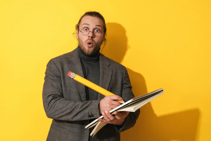 Homme drôle portant des lunettes, tenant un gros crayon et un carnet sur fond jaune