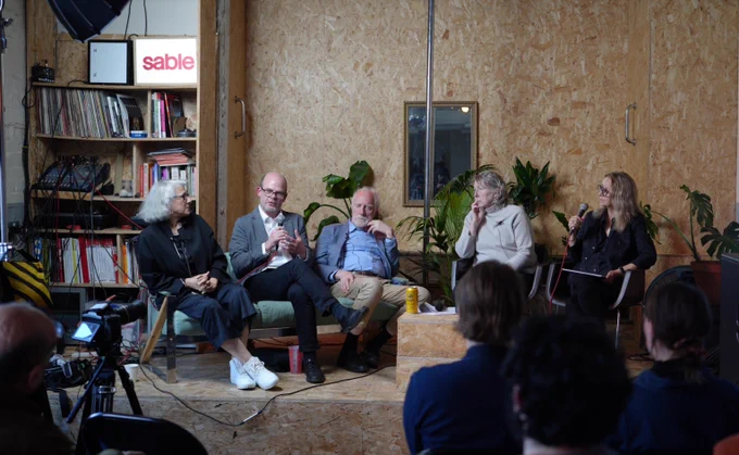 group of artists producers and architects sitting in chairs with sound equipment and drinks