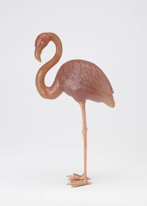 “A flamingo, carved in pink agate with rose diamond eyes and chased dull red gold legs.

Cartier, one of Fabergé’s competitors, chose to produce hardstone flamingos inspired by Fabergé’s work. The Royal Collection contains an example which appears stylised and unnaturalistic by comparison with this skilfully executed model.”