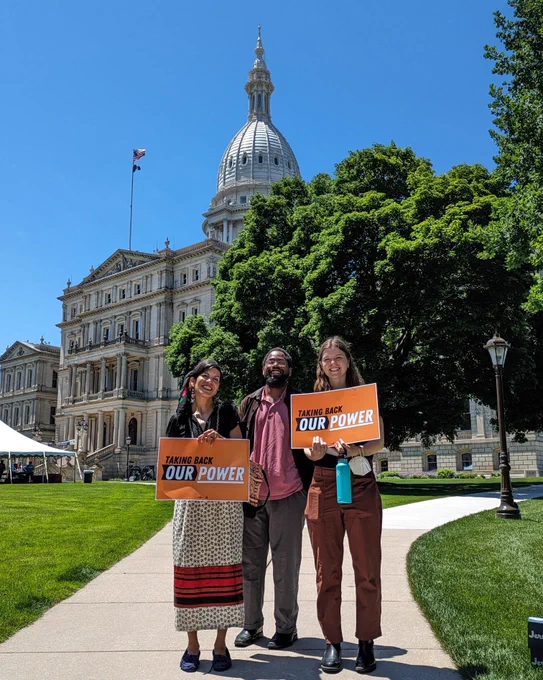 Clean Water Action staff in front of the MI Capitol holding Taking Back Our Power signs