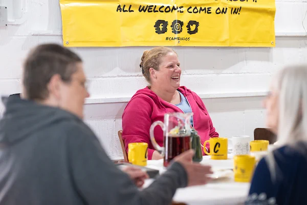 Group of people sat in a public living room laughing.