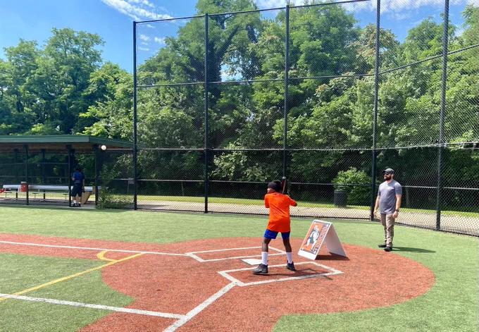 A youth baseball player prepares to swing at a pitch.