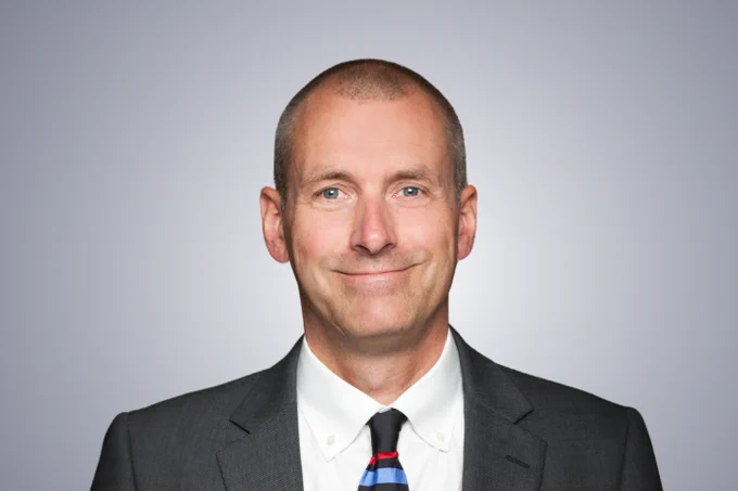  John M. Richardson wearing a suit and tie smiling at the camera.