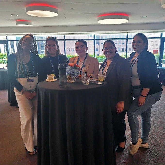 Five conference attendees standing around a table and smiling at the camera at Tessitura’s reception at the League of American Orchestras National Conference.