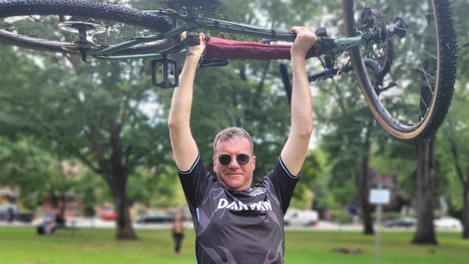 John Richmond holding a bike above his head