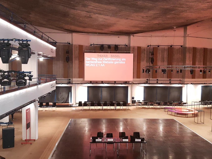 Foyer des Theaters Basel, Text auf Leinwand: Der Weg zur Zertifizierung als barrierefreie Website gemäss WCAG 2.1 AA