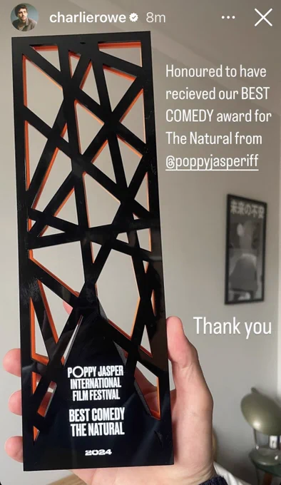 A hand holds up a black award that is like a black tower made of criss crossing bars like scaffolding.