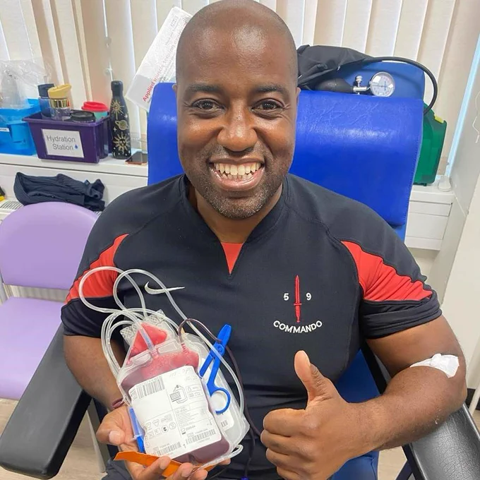 Blood donor Delon holding his donation and giving a thumbs up