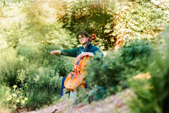 Connor Peterson, a senior in music, plays his cello in the greenspace between Love Library and Hamilton Hall while being filmed for a student spotlight by the Glenn Korff School of Music.