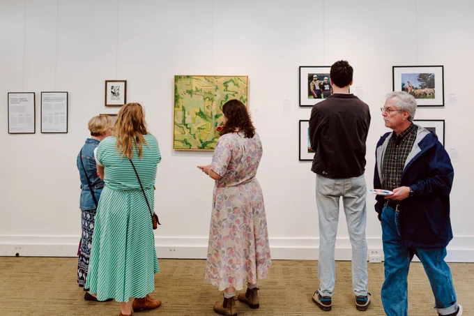 Five people viewing painting and photography work.