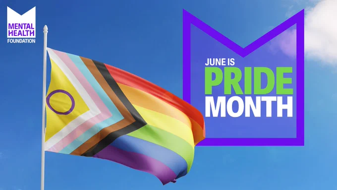 The image shows the LGBTQIA  flag against a blue sky background. There is an M shaped graphic above, with the text inside: "June is Pride Month". In the top right, there's the Mental Health Foundation logo. 