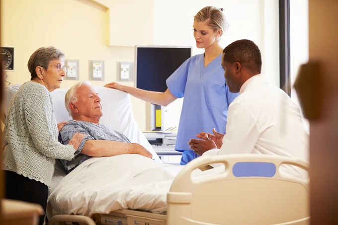 Picture of people talking to an older person in a hospital bed