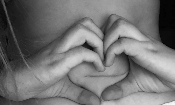A close-up of Allie's abdominal scar with Allie's hand making a heart shape around it.