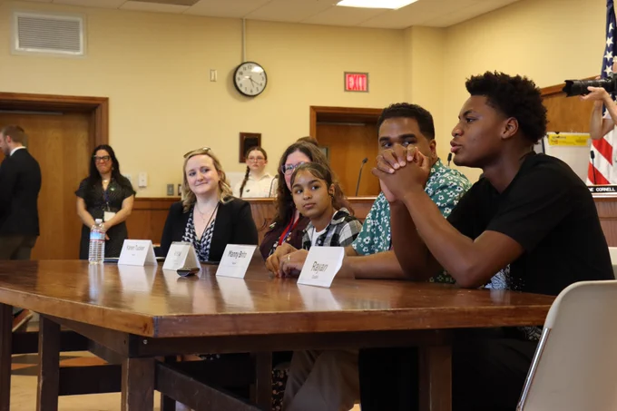 Students and faculty at Collins Middle School speak at a table.