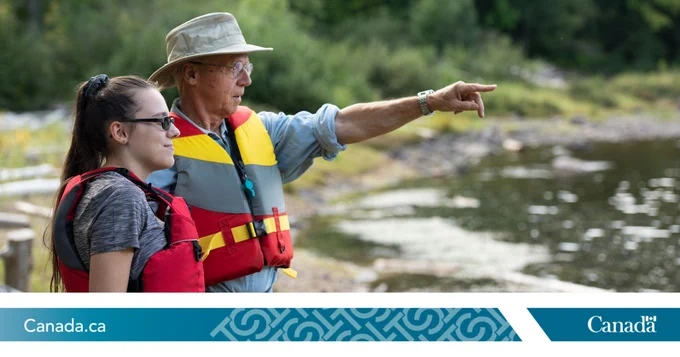 Un homme et une femme portant des gilets de sauvetage au bord de l'eau.