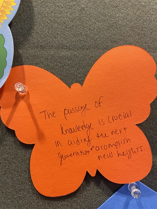 Orange paper butterfly with text that reads: The passage of knowledge is crucial in aiding the next generation to accomplish new heights.