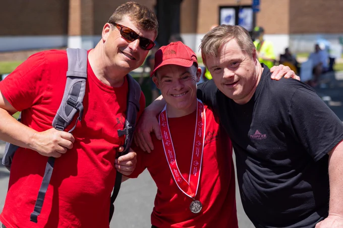 KMann smiles with an athlete and their father.