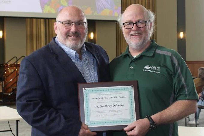 Geoff Dabelko and Sam Crowl pose for a picture together at the award ceremony, along with holding up Dabelko's award plaque. 