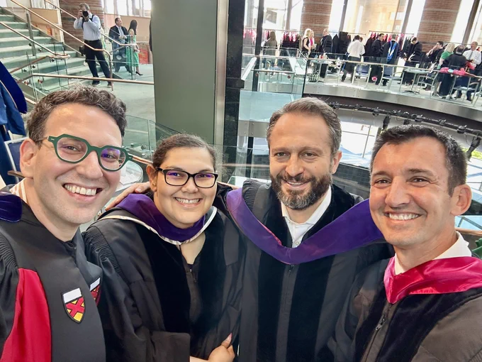 Four people in robes smiling to the camera