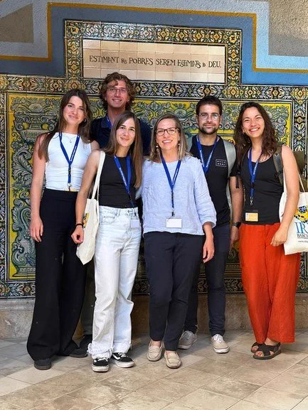 Group of six people looking at the camera, with blue conference lanyards and badges 