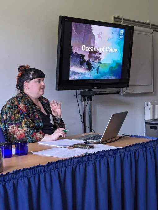 Rebecca sat at a desk in a smaller breakout room with Oceans of Value on the screen 