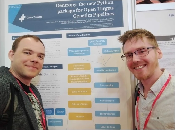 Two men stand on either side of a poster and smile at the camera. The poster title reads: Gentropy, the new Python package for Open Targets Genetics pipelines