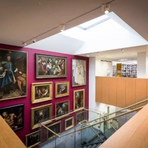 Wellcome Collection staircase with paintings and library shelves upsatirs
