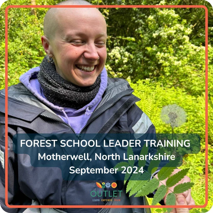 a forest school trainee smiling while taking part in their training. stood in a green woodland