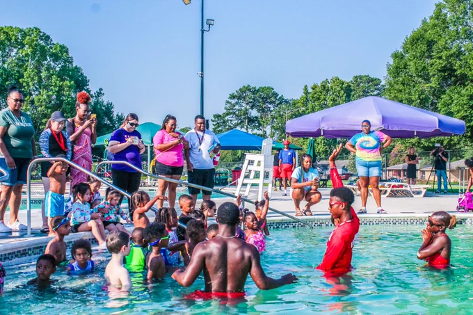 🌊🏊‍♀️ Make a splash and learn to swim at BREC's Largest Swim Lesson at Liberty Lagoon on June 28 at 8:30 am! 🌞🏖️ This free event is open to ages 3-99  and aims to teach the life-saving skill of swimming to prevent drowning. 💦💙 Pre-register now to secure your spot—registration is open and limited to 300 participants. Dive into safety with us!

Children and adults enjoying a sunny day at a crowded outdoor public swimming pool, with some children playing in the water and others waiting to enter.